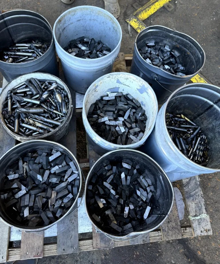 Buckets of used carbide inserts and end mills on a pallet